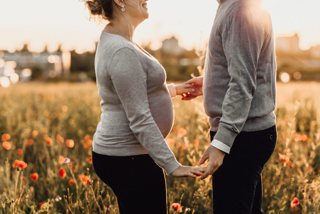 Paar steht sich gegenüber. Die Frau hat einen Babybauch. Sie tanzen im Mohnfeld in Laatzen.