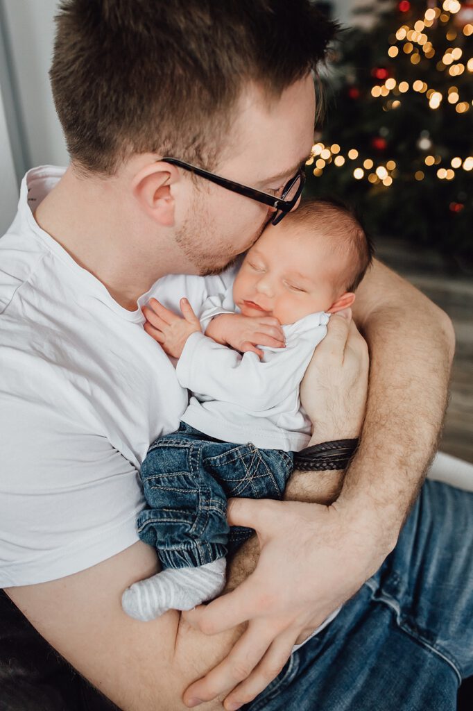 Papa hält Baby im Arm und küsst den Kopf