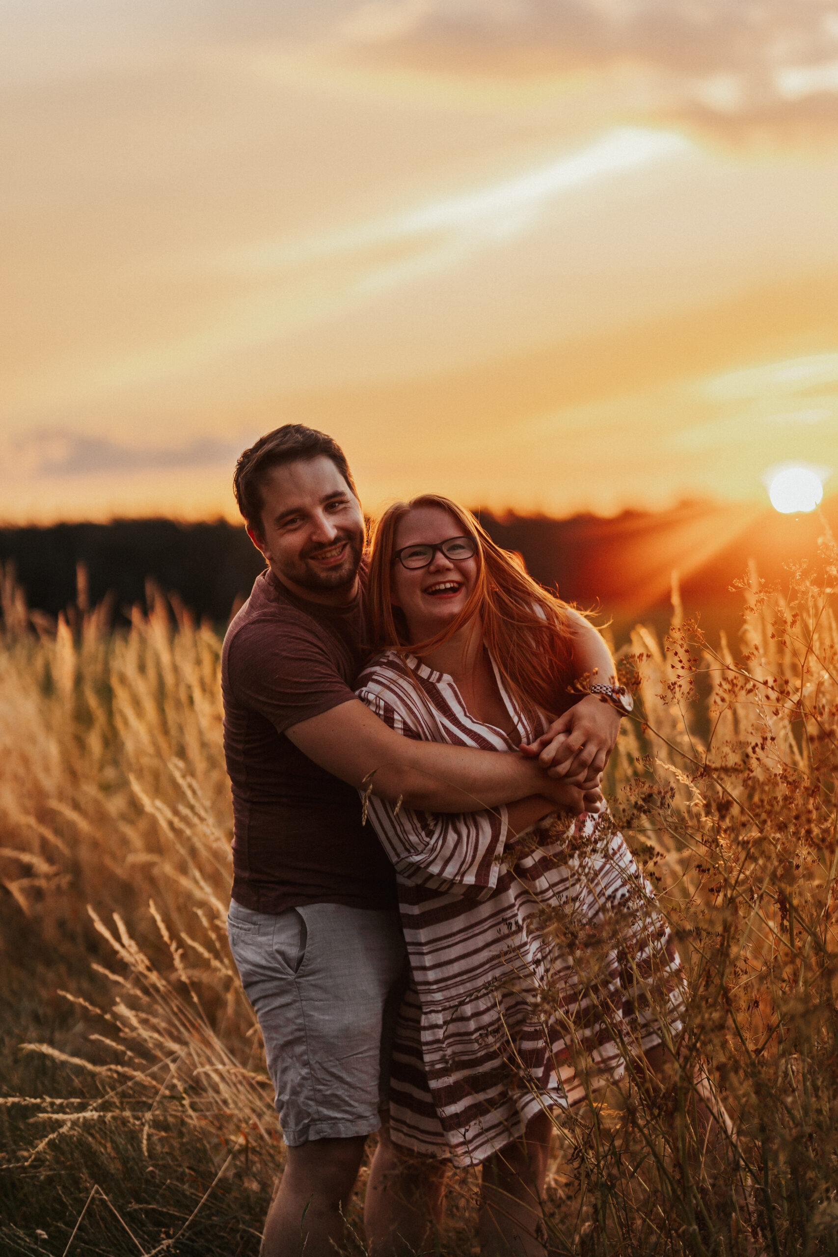 Lachendes Pärchen in Feld im Sonnenuntergang