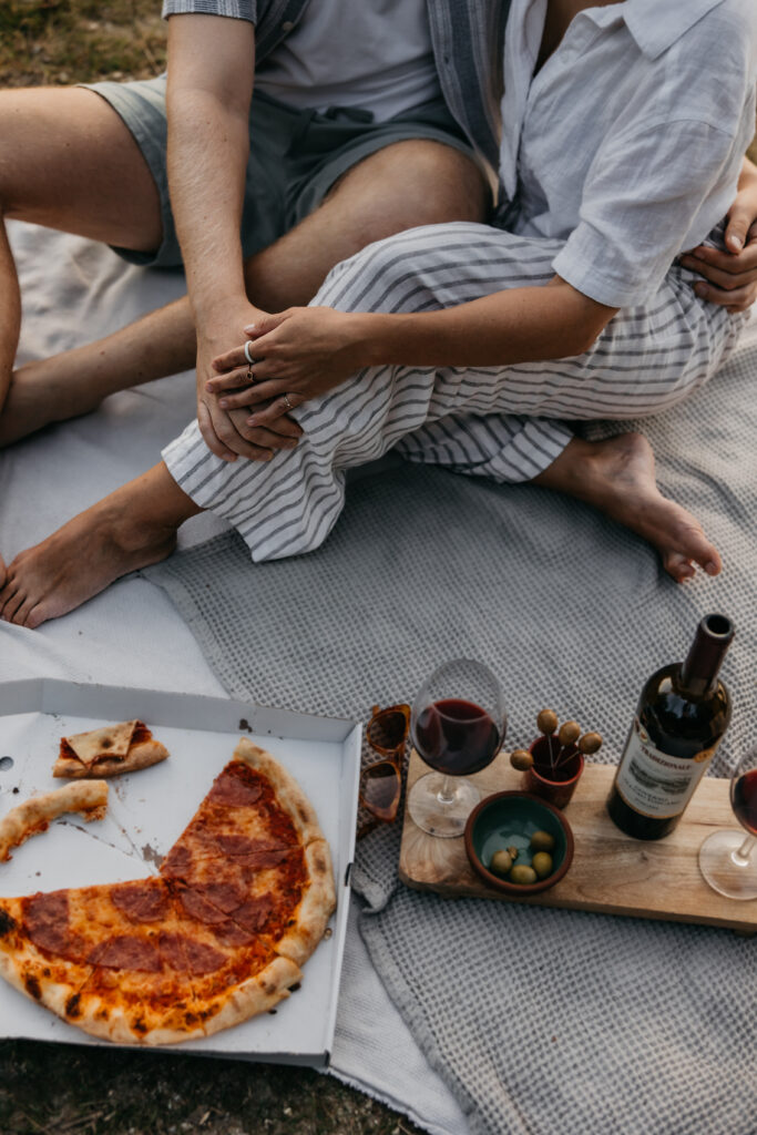 Detailaufnahme eines Picknick-Setups mit Pizza, Wein und Oliven