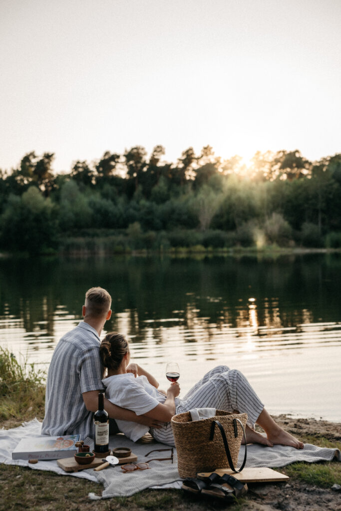 Frau lehnt sich entspannt an ihren Partner am Seeufer