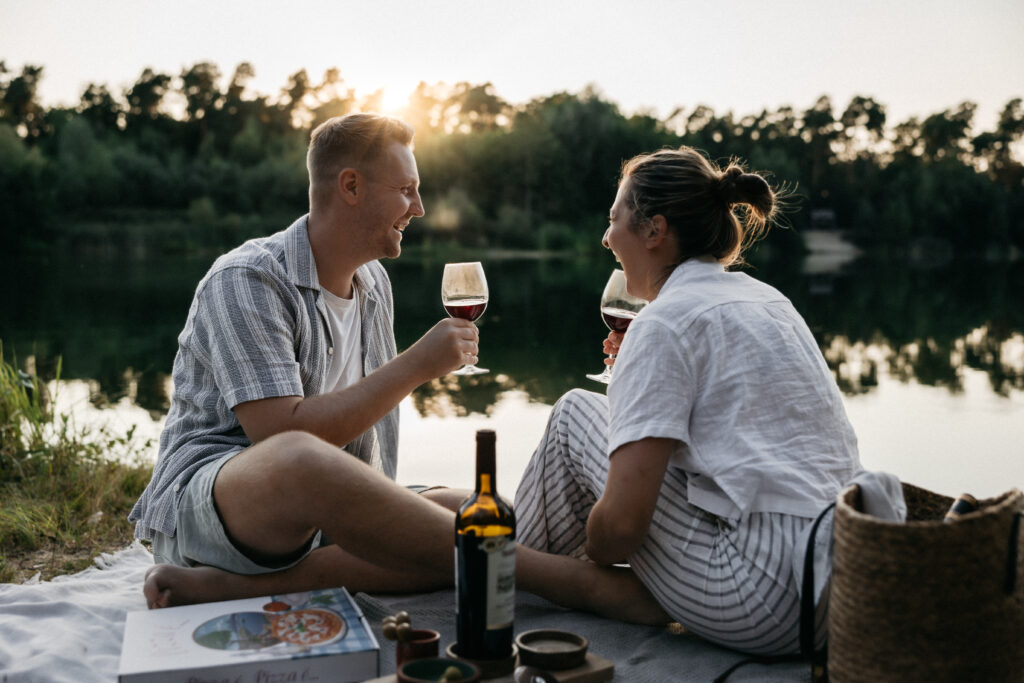 Paar lacht gemeinsam während eines Picknicks am See